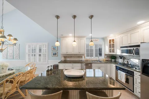 a kitchen with stainless steel appliances granite countertop a sink a stove and a wooden cabinets