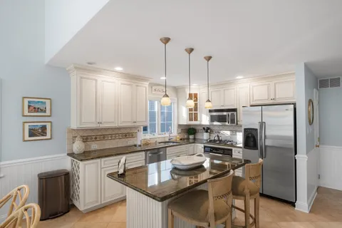 a kitchen with kitchen island a refrigerator stove and sink