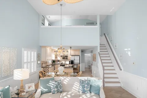 a living room with furniture kitchen view and a chandelier
