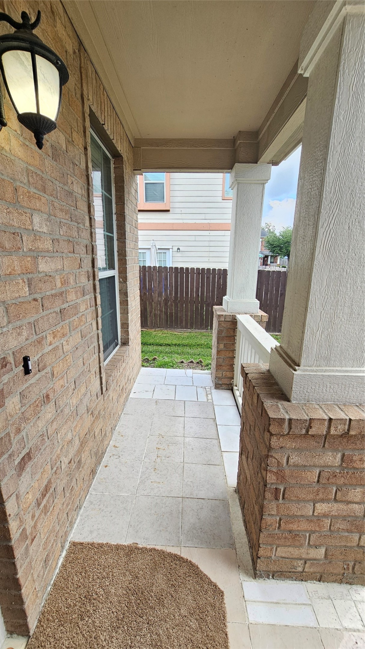 7918 Barnes Ridge Lane Houston, TX 77072 - Photo 2 of 34 This photo shows a cozy front porch with brick walls, a tiled floor, and a classic lantern-style light fixture.