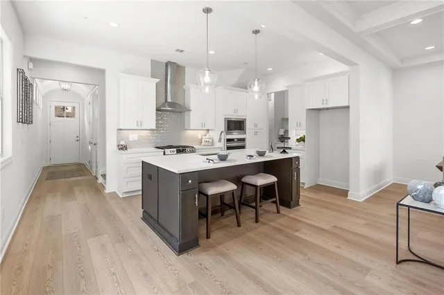 a large kitchen with stainless steel appliances kitchen island granite countertop a large stove a sink dishwasher and a refrigerator with wooden floor