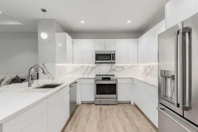 a kitchen with stainless steel appliances white cabinets white stove a microwave and a refrigerator