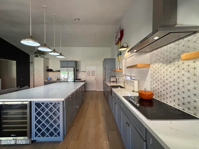 a kitchen with stainless steel appliances granite countertop a sink a stove and a wooden floor