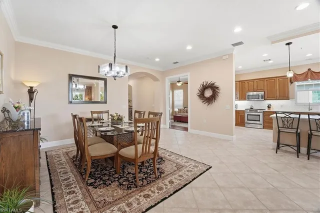 a dining hall with stainless steel appliances kitchen island granite countertop a table and chairs in it