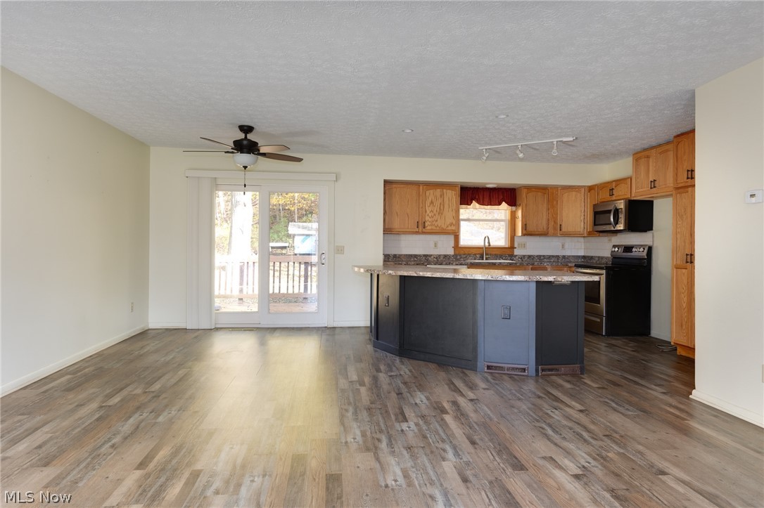 9416 Kieffer Road Mantua, OH 44255 - Photo 10 of 29 Kitchen featuring dark wood-type flooring, appliances with stainless steel finishes, a textured ceiling, a ceiling fan, and a center island