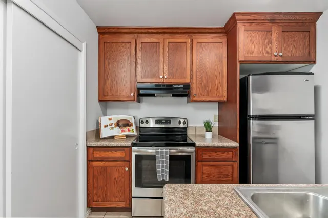 a kitchen with stainless steel appliances granite countertop a refrigerator and a stove top oven