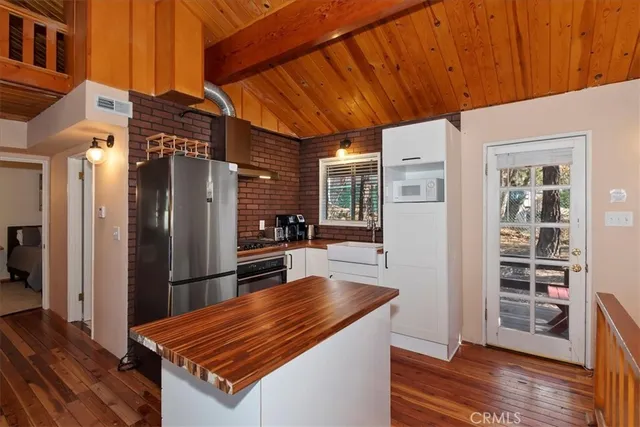 a living room with stainless steel appliances furniture a refrigerator and wooden floor