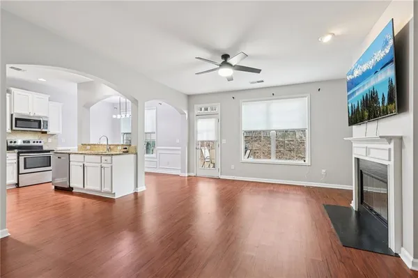 a view of an empty room with wooden floor and a kitchen