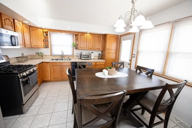 a kitchen with stainless steel appliances granite countertop a stove a sink dishwasher a dining table and chairs with wooden floor