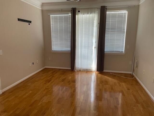 9833 Baywinds Boulevard, Unit 7108 West Palm Beach, FL 33411 - Photo 4 of 10 an empty room with wooden floor and windows