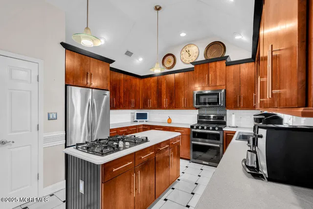 a kitchen with stainless steel appliances granite countertop a stove a refrigerator a oven a kitchen island a dining table and chairs with wooden floor