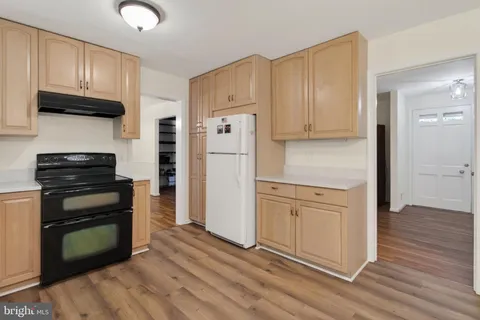 a kitchen with granite countertop a refrigerator stove and wooden cabinets