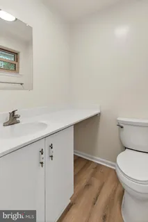 a bathroom with a toilet a sink and wooden floor