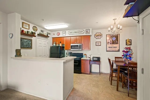 a kitchen with stainless steel appliances kitchen island granite countertop a refrigerator and a dining table