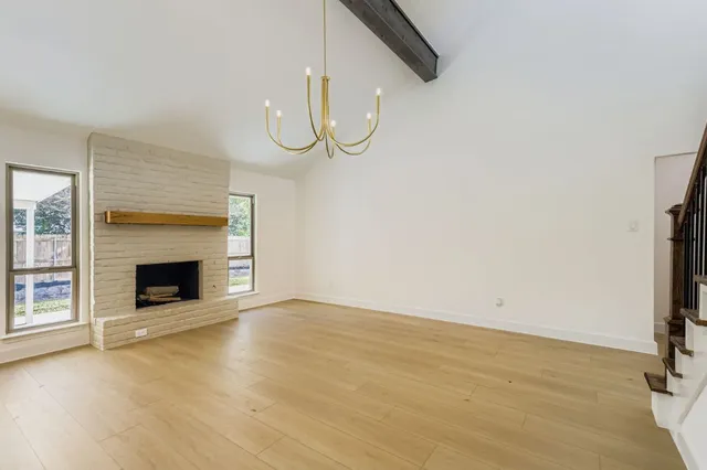 a view of an empty room with wooden floor fireplace and a window