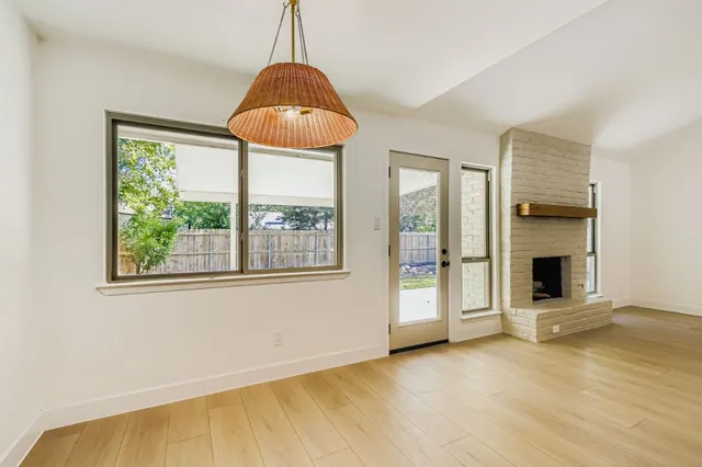 a view of an empty room with window and chandelier fan