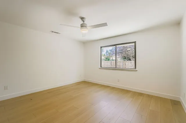 an empty room with a window and ceiling fan