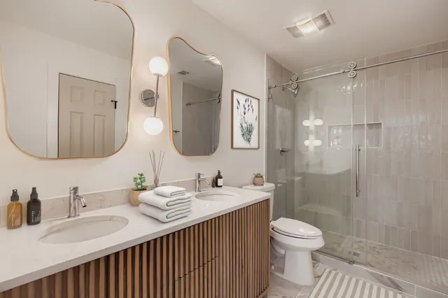 a bathroom with a double vanity sink toilet mirror and shower