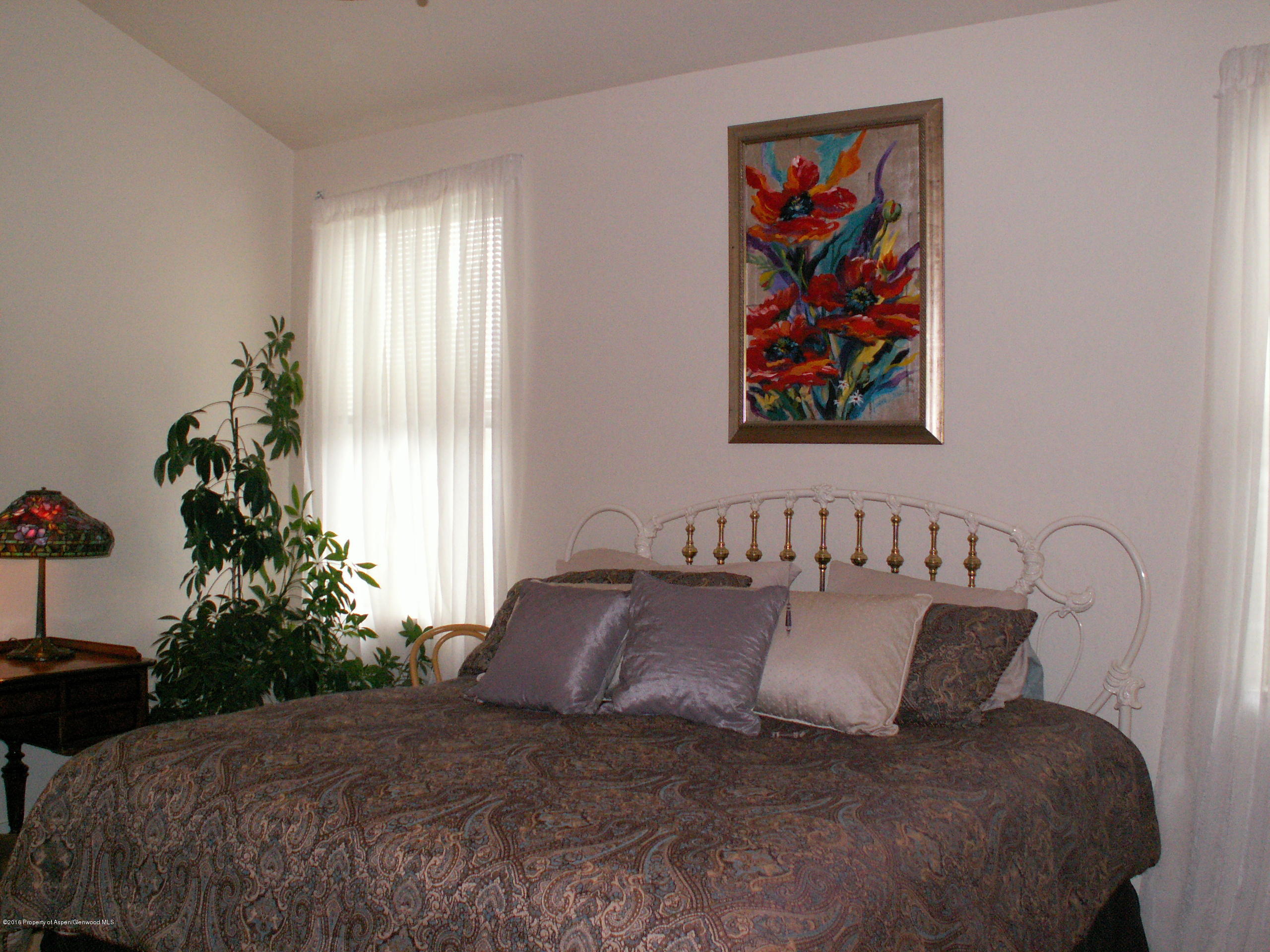 413 Jody Road Basalt, CO 81621 - Photo 10 of 10 a large bed sitting in a bedroom next to a window with potted plants