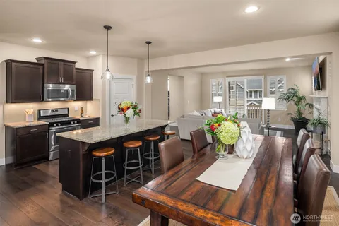 a kitchen with stainless steel appliances granite countertop a stove a refrigerator a kitchen island a dining table and chairs