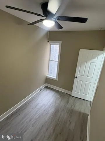 a view of an empty room with a window and wooden floor