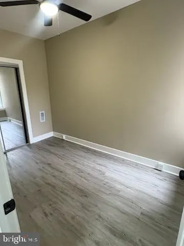 a view of an empty room with wooden floor and a chandelier