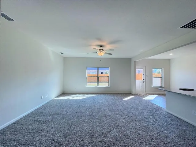an empty room with windows and fan