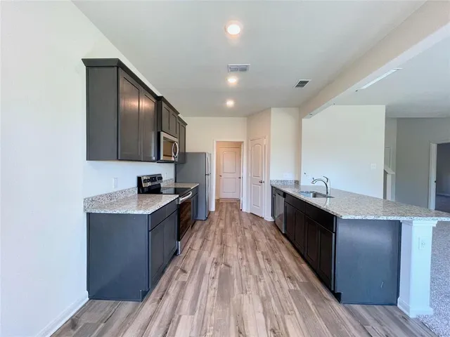 a large kitchen with granite countertop a large counter top space stainless steel appliances and cabinets