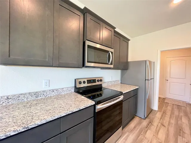 a kitchen with granite countertop cabinets stainless steel appliances and wooden floor