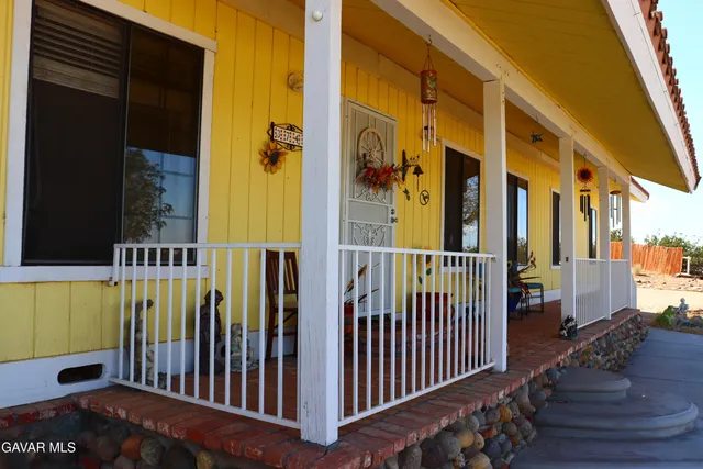 a view of a patio with table and chairs under an umbrella with a barbeque