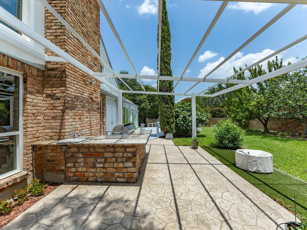 6160 Spring Valley Road Dallas, TX 75240 - Photo 35 of 40 Expansive outdoor patio featuring an attached pergola structure, a built-in brick barbecue station with countertop space, and stamped concrete flooring