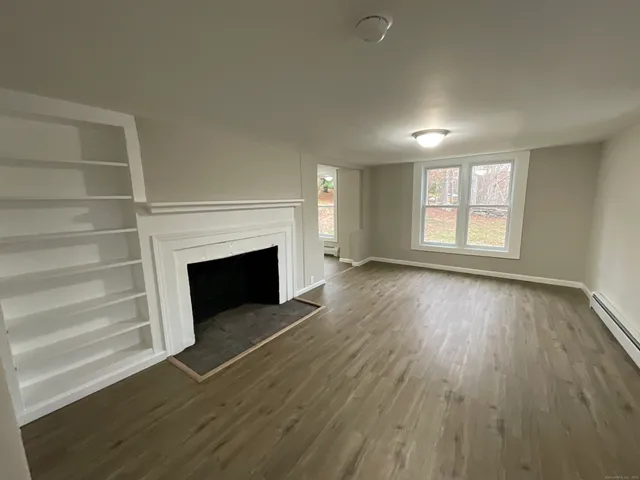 an empty room with wooden floor fireplace and windows