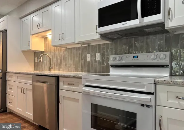 a kitchen with granite countertop white cabinets stainless steel appliances and a sink