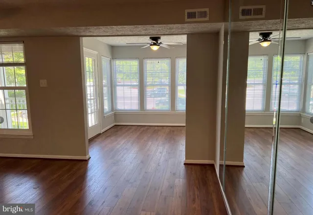 an empty room with wooden floor and windows