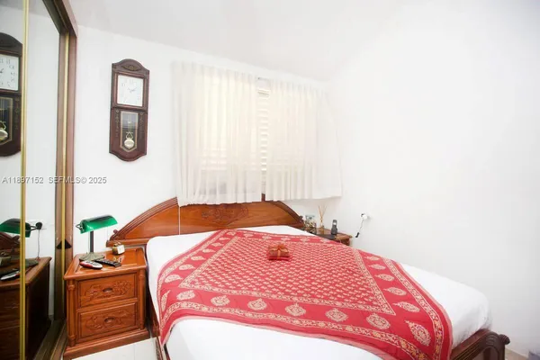 a bedroom with two beds and next to a window