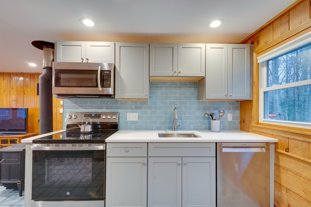 100 Dunn Road Ashburnham, MA 01430 - Photo 17 of 31 a kitchen with stainless steel appliances granite countertop a stove a sink a microwave a refrigerator and white cabinets