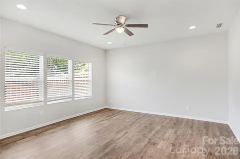an empty room with windows and ceiling fan