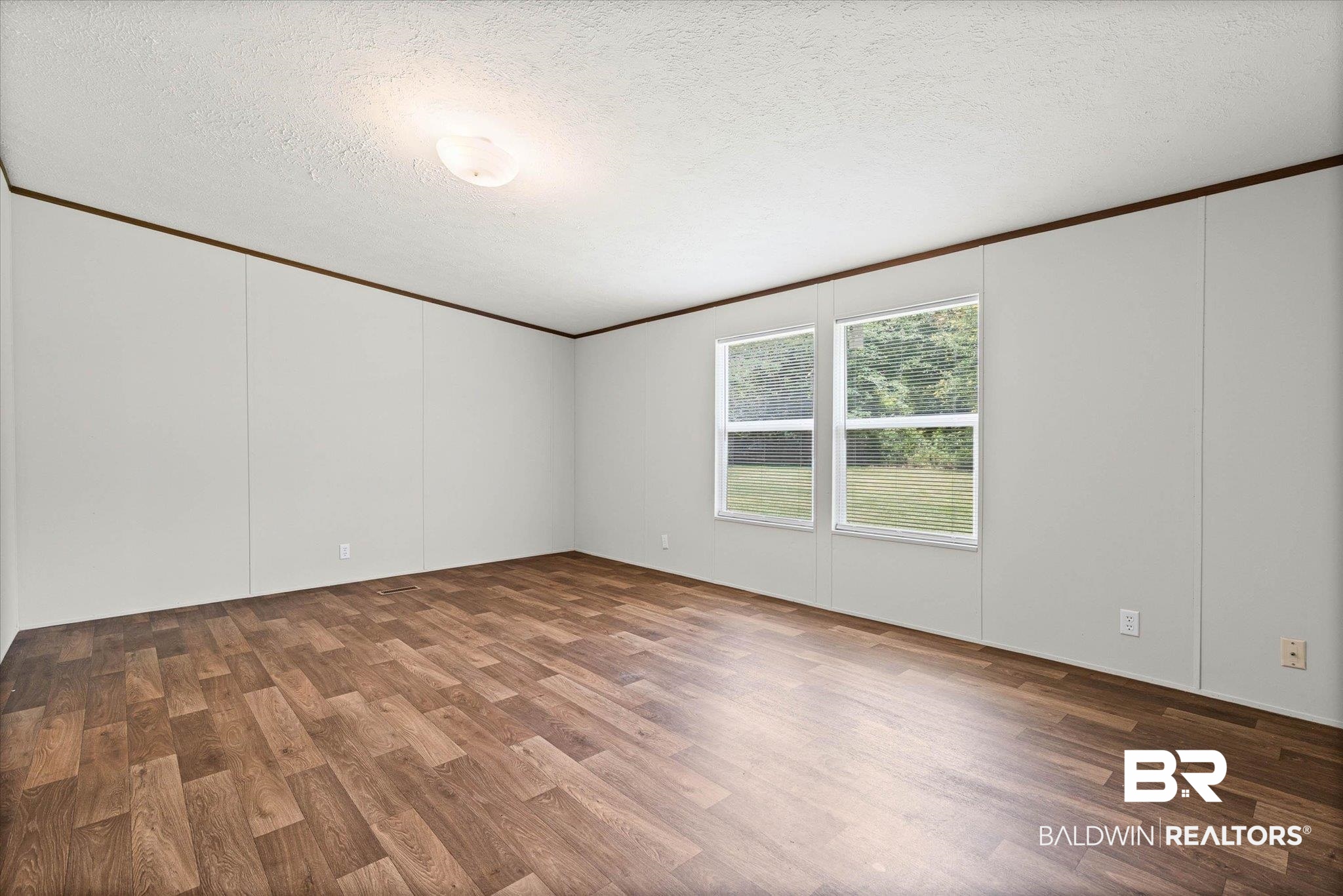 25366 Pollard Road Daphne, AL 36526 - Photo 11 of 22 Spacious room featuring wood-finish flooring, light-toned walls, and twin windows