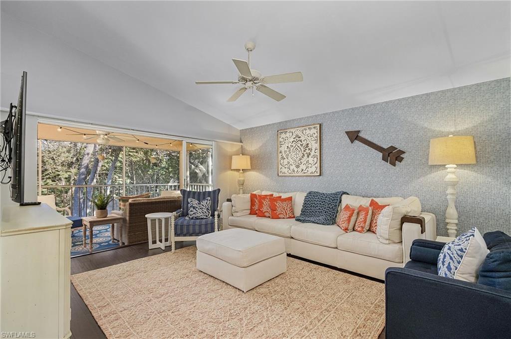3785 Fieldstone Boulevard, Unit 208 Naples, FL 34109 - Photo 1 of 26 Living room featuring lofted ceiling, decorative walls, ceiling fan, and wood floors