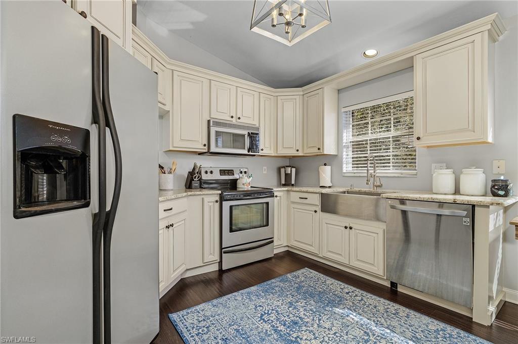 3785 Fieldstone Boulevard, Unit 208 Naples, FL 34109 - Photo 6 of 26 Kitchen featuring appliances with stainless steel finishes, cream cabinets, a sink, and wood floor
