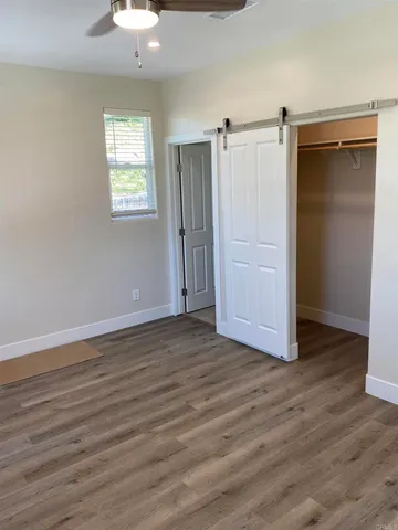 an empty room with wooden floor closet and windows