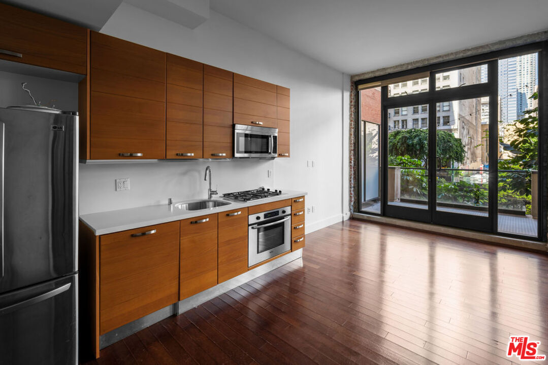 460 South Spring Street, Unit 205 Los Angeles, CA 90013 - Photo 3 of 21 a kitchen with stainless steel appliances granite countertop a stove a sink and a refrigerator