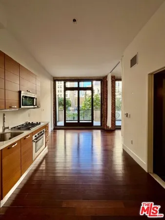 a large kitchen with stainless steel appliances granite countertop a stove top oven a sink dishwasher a microwave oven and a dining table with wooden floor