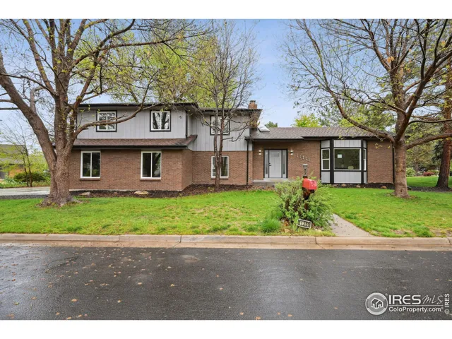 a front view of a house with a garden and trees