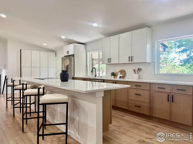 a kitchen with kitchen island granite countertop a table chairs sink and cabinets