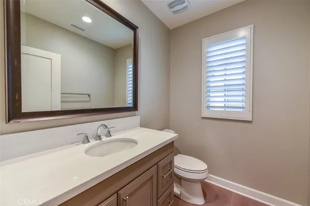 a bathroom with a granite countertop sink toilet and mirror
