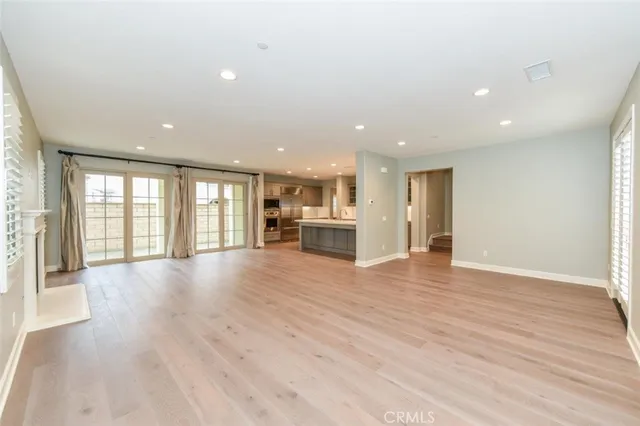 a view of an empty room with wooden floor and windows