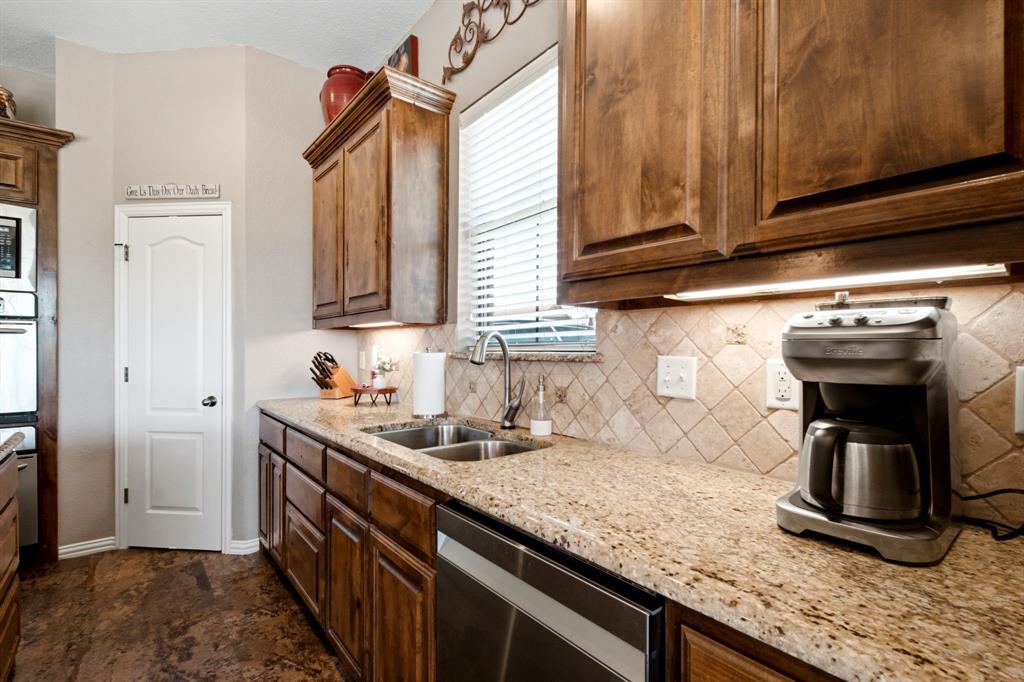 600 Aspen Street Pilot Point, TX 76258 - Photo 21 of 39 Kitchen featuring wood-finish cabinetry, granite countertops, tile backsplash, and stainless steel undermount sink