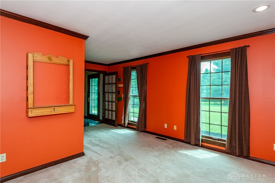 9981 Ridge Acres Lane Englewood, OH 45322 - Photo 19 of 73 This vibrant room features large windows and elegant crown molding, creating an inviting atmosphere.