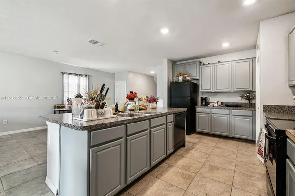 a kitchen with kitchen island granite countertop a sink counter top space appliances and cabinets